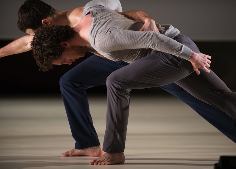 Two men lunge side by side, their heads face the floor